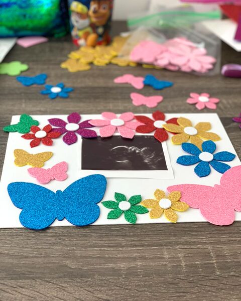 La ecografía de mi hija enmarcada en una cartulina con flores y mariposas de foami escarchado.