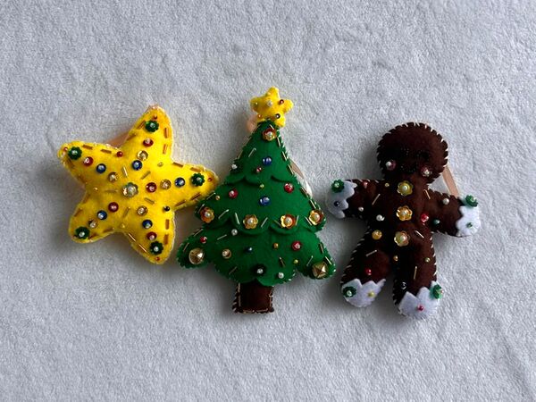 El set Navidad clásica en fila sobre una cobija blanca: una estrella amarilla, un arbolito verde y una galleta de jengibre.